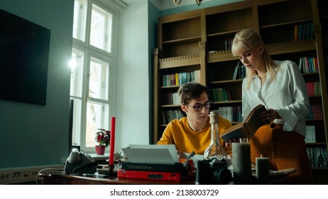 Beautiful Young Caucasian Couple In A Fancy Vintage Looking Study Learning New Information From Their Home Library Selection. Handsome Brunette Writer Getting Tips From His Gorgeous Blonde Girlfriend