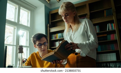 Beautiful Young Caucasian Couple In A Fancy Vintage Study Learning New Information. Handsome Brunette Writer Getting Tips From His Blonde Girlfriend In Their Home Library.