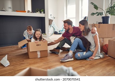 Beautiful Young Caucasian Family Playing All Together With Their Dog In New Empty Apartment