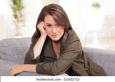 Beautiful young Caucasian female relaxing on grey chair at home with long brown hair. - Shutterstock ID 111432713