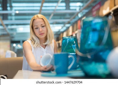 Beautiful Young Caucasian Woman Choosing The Right Item For Her Apartment In A Modern Home Decor Furnishings Store. Shopping In Retail Store.