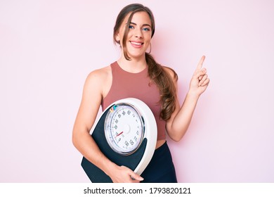 Beautiful Young Caucasian Woman Holding Weight Machine To Balance Weight Loss Smiling Happy Pointing With Hand And Finger To The Side 