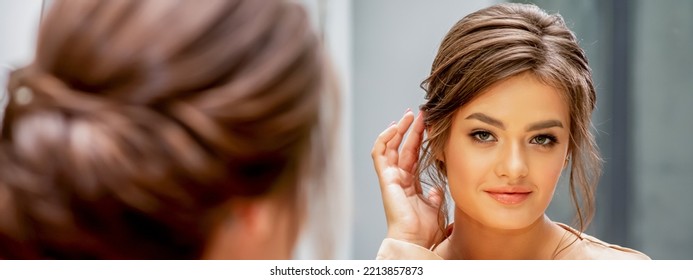 Beautiful Young Caucasian Woman Looking At Her New Haircut In The Mirror Touches Hairstyle