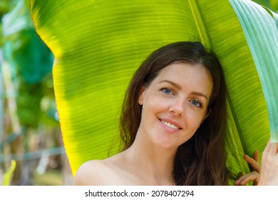 Beautiful Young Caucasian Woman Portrait Near Banana Palm Leaves Tropical Plants In Jungle. Skin Care And Natural Organic Beauty Concept. High Quality Photo