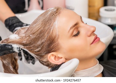 Beautiful young caucasian woman receiving wash her hair in a hair salon - Powered by Shutterstock