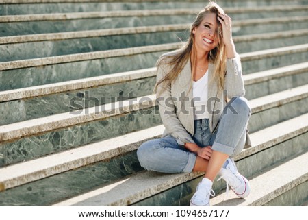 Blonde young caucasian woman smiling on steps