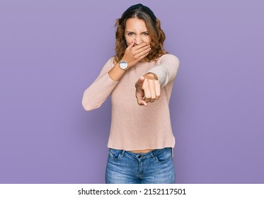 Beautiful Young Caucasian Woman Wearing Casual Sweater Laughing At You, Pointing Finger To The Camera With Hand Over Mouth, Shame Expression 