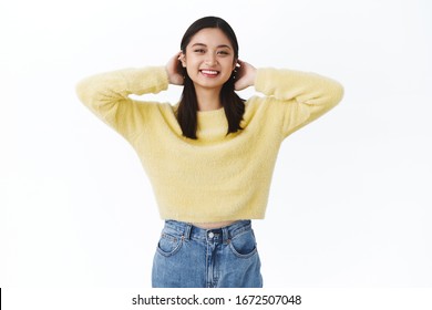 Beautiful Young Charismatic Asian Girl In Yellow Sweater Brushing Hair Behind Ears Cute, Smiling Kawaii, Express Carefree And Happy Emotiones, Being Positive, Enjoying Spring Sunny Days