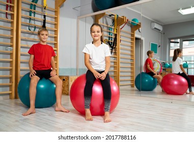 Beautiful young children sitting on Swiss balls in the gym, physical wellbeing 