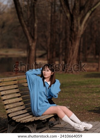 Similar – Junge Frau sitzt auf einer Bank in einem Park in ruhiger Pose.