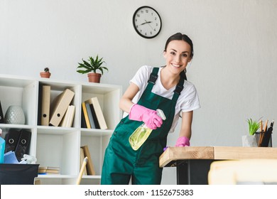 Beautiful Young Cleaner Holding Spray Bottle With Detergent And Smiling At Camera While Cleaning Office