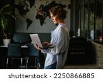 Beautiful young concentrated business woman wearing shirt using laptop while standing in modern workspace