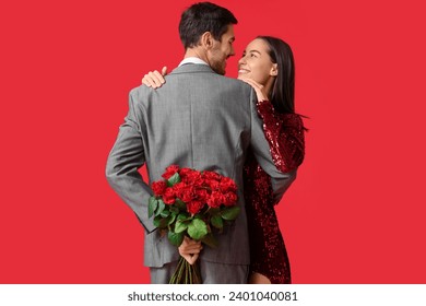 Beautiful young couple with bouquet of roses on red background. Valentine's day celebration - Powered by Shutterstock