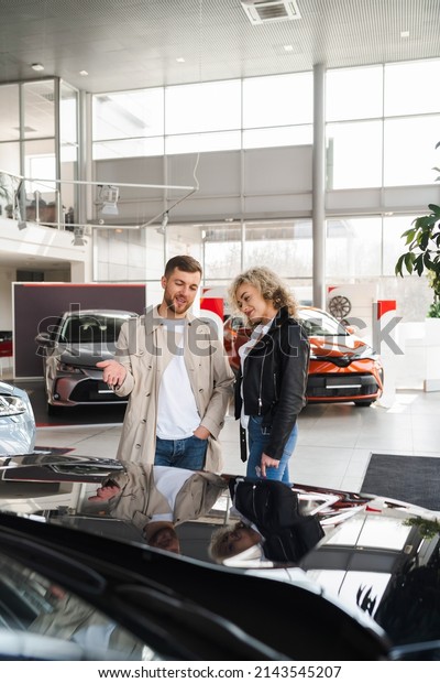 Beautiful\
young couple in a car dealership choose a\
car