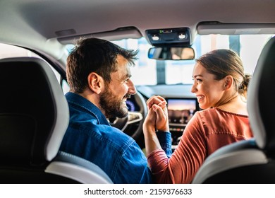 Beautiful Young Couple At Car Showroom Choosing A New Car To Buy.