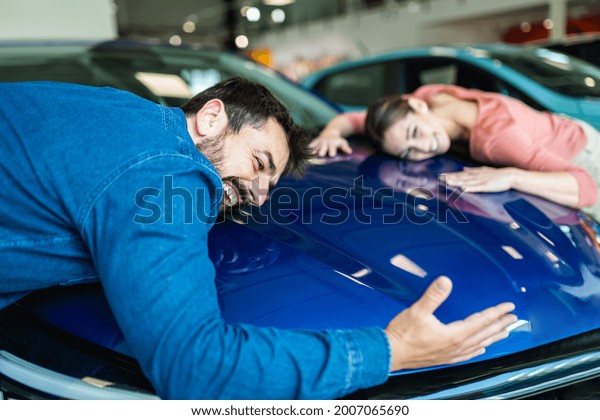 Beautiful young couple at car showroom choosing a\
new car to buy.