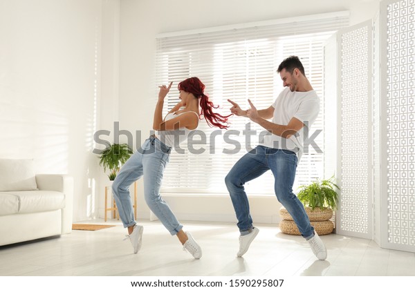 Beautiful young\
couple dancing in living\
room