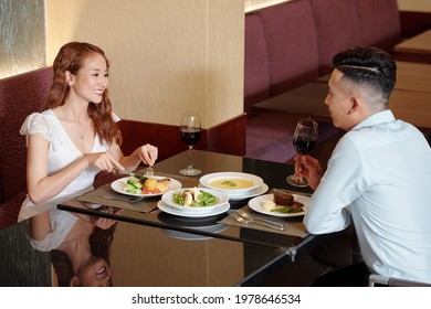 Beautiful Young Couple Drinking Wine, Eating Dinner And Talking In Fancy Restaurant