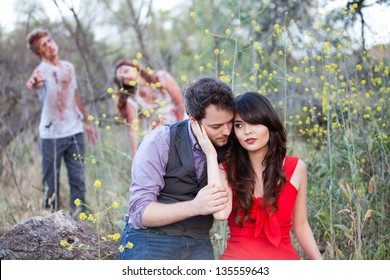 Beautiful Young Couple embracing with Zombies approaching