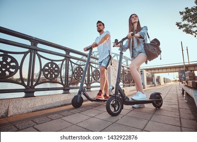 Beautiful young couple is enjoying sunny summer day while riding their own electro scooters. - Powered by Shutterstock