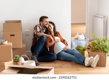 Beautiful young couple expecting a baby just moved into an empty apartment, sitting among cardboard boxes making plans for future. New beginnings - Powered by Shutterstock