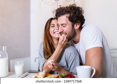 Beautiful young couple is feeding each other and smiling while cooking in kitchen at home. Happy sporty couple is preparing healthy food on light kitchen. Healthy food concept. - Powered by Shutterstock