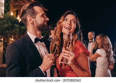 Beautiful young couple in formalwear toasting with champagne while spending time on luxury party