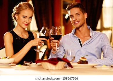 Beautiful Young Couple With Glasses Of Red Wine In Luxury Restaurant 