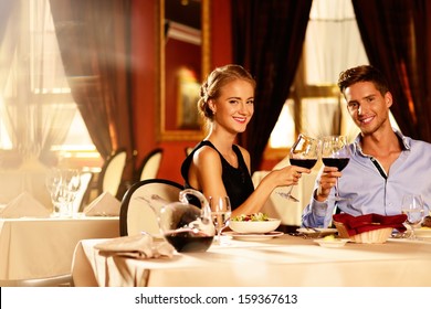 Beautiful Young Couple With Glasses Of Red Wine In Luxury Restaurant 