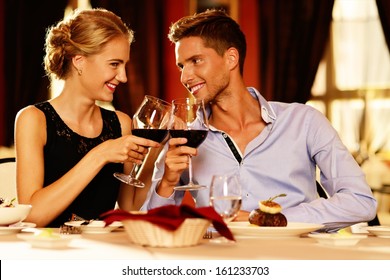 Beautiful Young Couple With Glasses Of Red Wine In Luxury Restaurant 