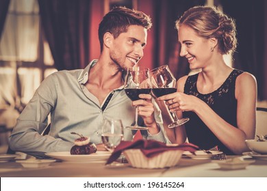 Beautiful young couple with glasses of red wine in luxury restaurant - Shutterstock ID 196145264