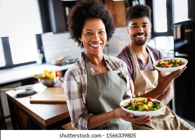 Beautiful young couple having fun and laughing while cooking in kitchen