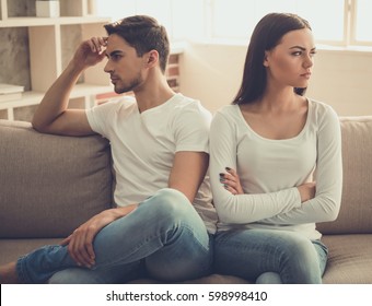 Beautiful young couple is having a quarrel while sitting on sofa at home