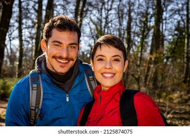 Beautiful young couple is hiking in the woods. The smiling couple looks into the camera. - Shutterstock ID 2125874075