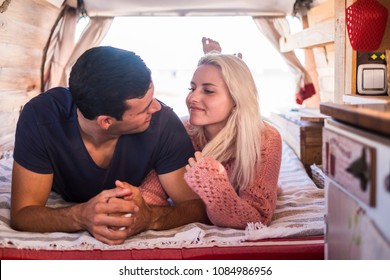 Beautiful Young Couple Look Eachother With Love Lay Down Inside An Old Vintage Van Like Home. Tiny House For Lover In Vacation For Alternative Day Life Like Hippy Modern.