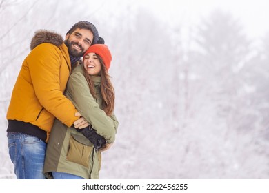 Beautiful young couple in love spending winter vacation in the mountains, hugging and relaxing outdoors on snowy winter day - Powered by Shutterstock