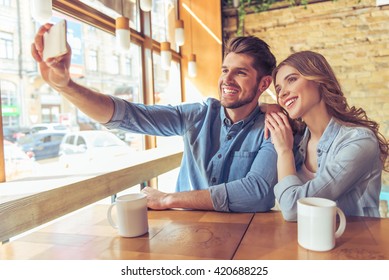 Beautiful young couple is making selfie using a smartphone and smiling while sitting in the cafe - Powered by Shutterstock