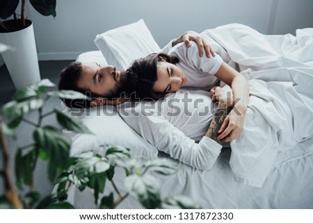 Similar – Young adult couple kissing each other on couch