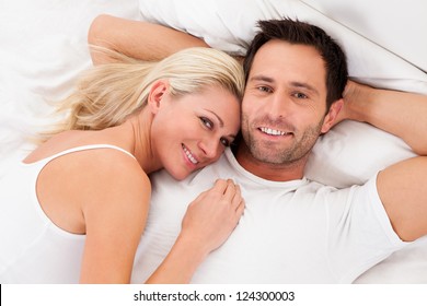 Beautiful Young Couple Relaxing In Bed At Home