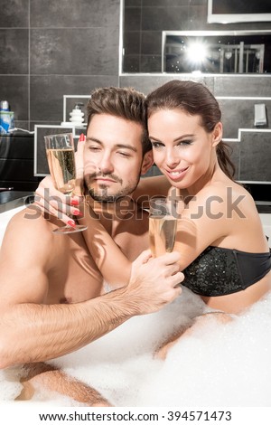 Beautiful young couple relaxing together and drinking Champagne in the Whirlpool.