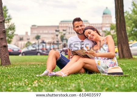 A beautiful young couple are siting in the grass having an ice-cream with the Castle in background in Budapest, Hungary.
