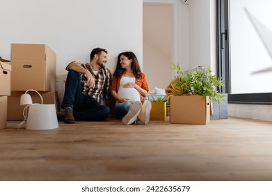 Beautiful young couple sitting among cardboard boxes in their new apartment making plans - Powered by Shutterstock