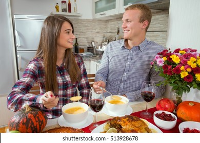 Beautiful Young Couple Is Sitting At The Dining Table And Enjoying Thanksgiving Meal. They Are Eating Homemade Soup And Looking At Each Other.