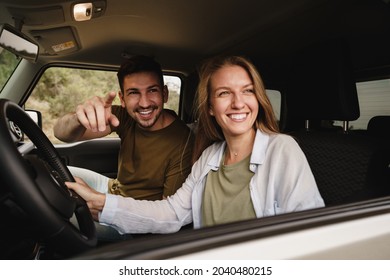 Beautiful young couple sitting on front passenger seats and driving a car
