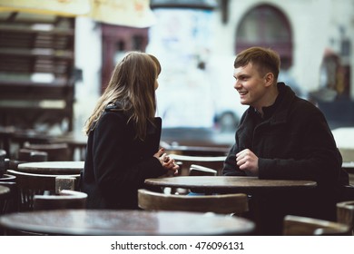 Beautiful And Young Couple Sitting Outside A Cafe