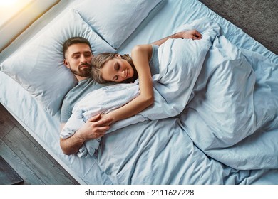 Beautiful young couple sleeping in bed hugging. Calm and healthy sleep. Top view. - Powered by Shutterstock