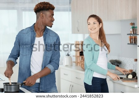 beautiful young couple is smiling while cooking