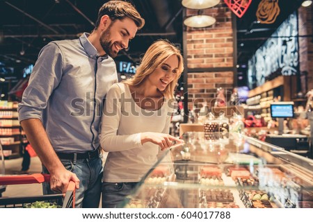 Beautiful young couple is smiling while doing shopping at the supermarket