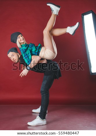 Beautiful young couple in the studio. Girl and guy having fun and laughing.