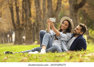 Beautiful young couple taking selfie in park. Space for text - Powered by Shutterstock